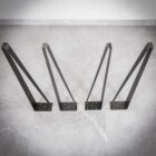 Fyra svarta metallbordben mot grått golv.