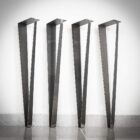 Fyra svarta stålbordsben mot vit vägg.