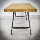 Träbänk med metallben på marmorgolv.