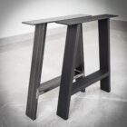 Svarta metallbordsben på grått golv.