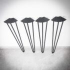 Fyra svarta metallben mot vit vägg.