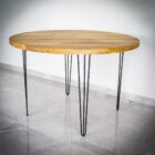 Runt träbord med metallben på klinkergolv.