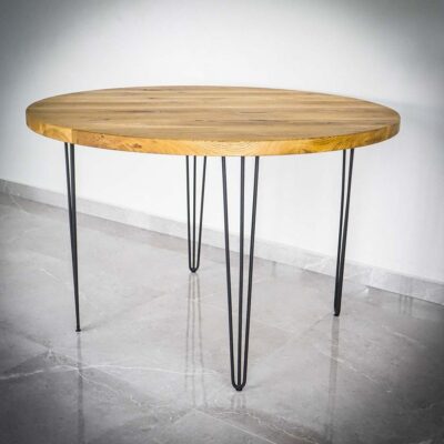 Runt träbord med metallben på klinkergolv.