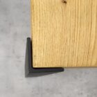 Hörnsats i svart metall på träbordshörn.