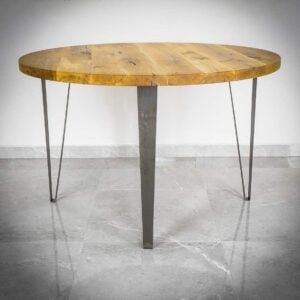 Runt träbord med metallben på stengolv.