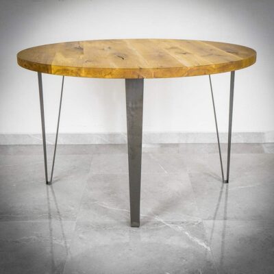 Runt träbord med metallben på stengolv.