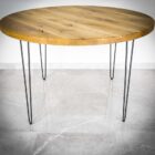 Runt träbord med metallben på stengolv.