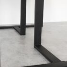 Svarta, moderna bordsben på betonggolv.