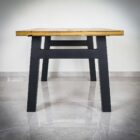 Träbord med svarta metallben på marmorgolv.