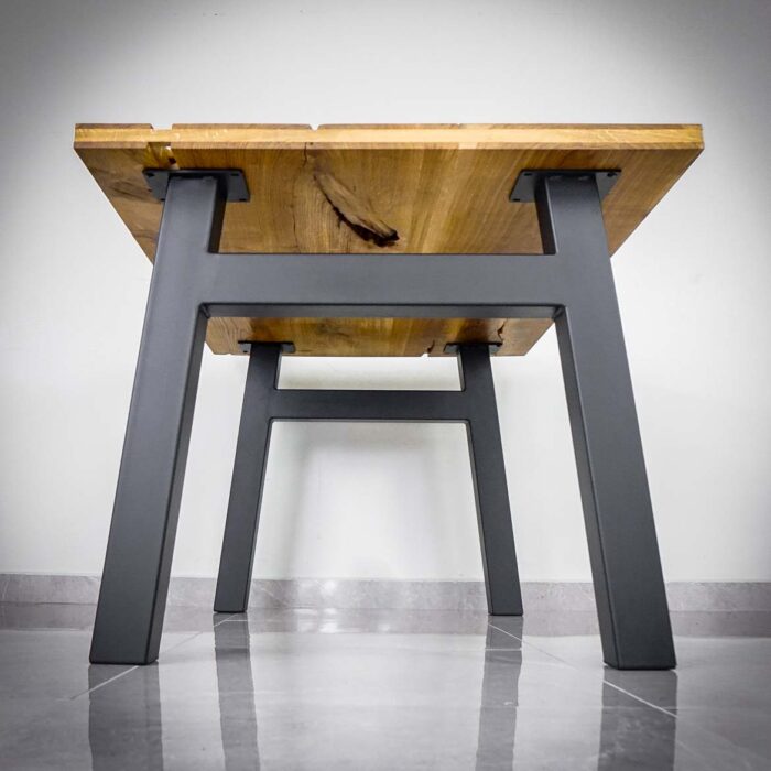 Bordsben Magna H 4 Svart metallbord med träskiva, fotograferat från sidan.