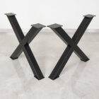 Svarta metallbordsben i kryssform på golvet.