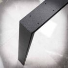 Svart metallben på grå yta