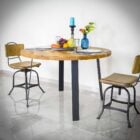 Runt matbord med fruktskål och två stolar.