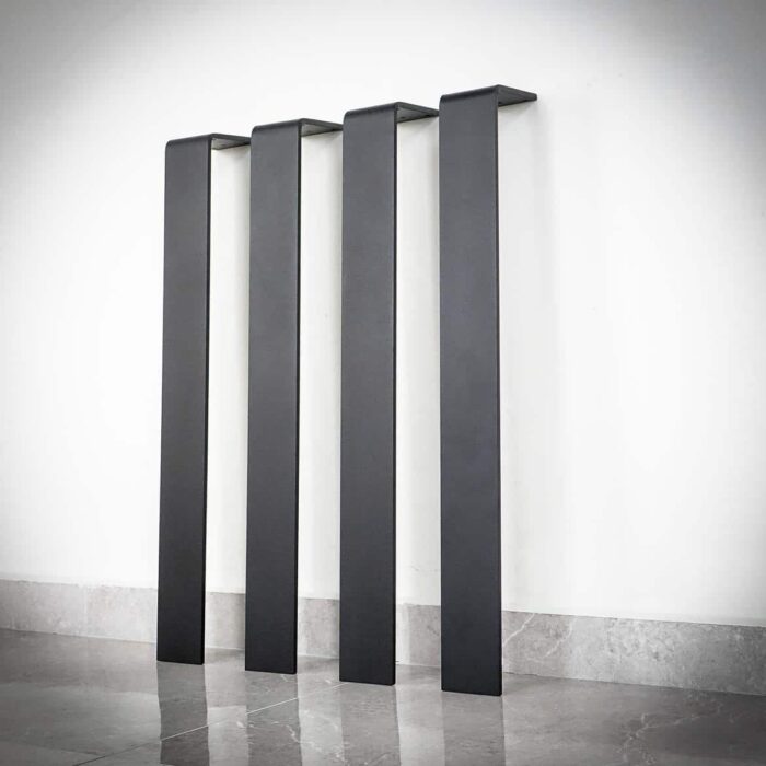 Bordsben-Platt-3-1.jpg Svarta väggmonterade metallhandtag vid golvet.