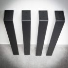 Fyra svarta bordsben mot en vägg.