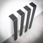 Fyra svarta bordsben mot en vägg.