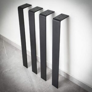 Fyra svarta möbelben mot vit vägg.