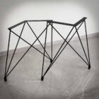 Metalbordstativ med geometrisk design på kakelgolv.