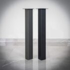 Två svarta metallstolpar på grått golv.