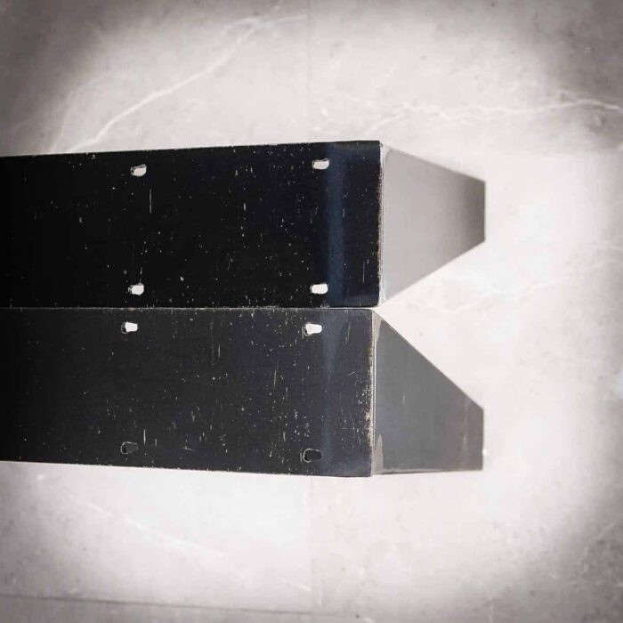 Bordsben-TILT-7 Två svarta metallhyllor med hål för skruvar.