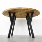 Runt träbord med metallben på grått golv.
