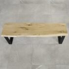 Träbänk med metallben på stengolv.