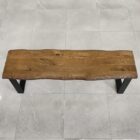 Träbänk med metallben på stengolv.