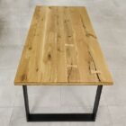 Rektangulärt träbord med metallben på stengolv.