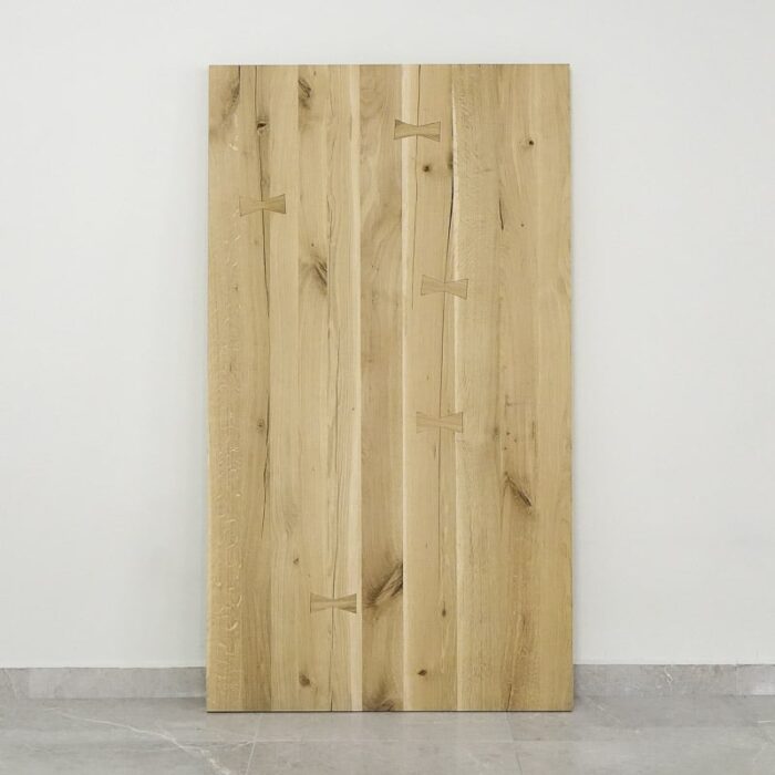 Bordsskiva-Antique-1-obehandlad11.jpg Träbordsskiva med fjärilsskarvar mot vit vägg.