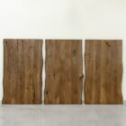 Tre stående träpaneler mot vit vägg.