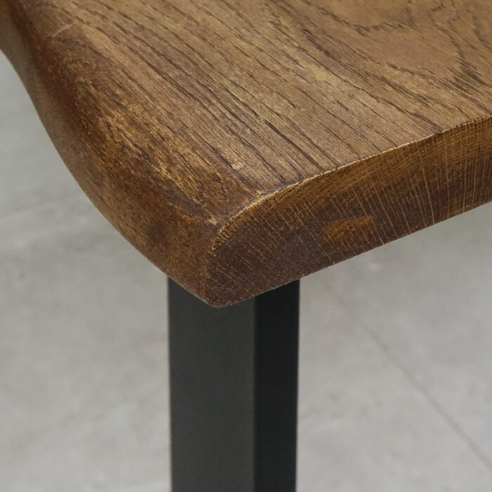 Bordsskiva-Live-Edge-1-Grundoljad-Brun4.jpg Hörnet av ett träbord med metallben.