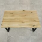 Träbord med svarta ben på stengolv.