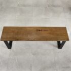 Träbänk på grått klinkergolv.