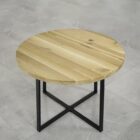 Runt träbord med metallben på grått golv.