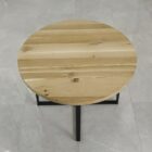 Runt träbord med metallben på stengolv.