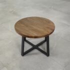 Runt träbord med metallben på stengolv.