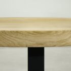 Närbild av träbordsskiva med svart ben.