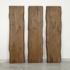 Tre rustika träplankor mot vit vägg.