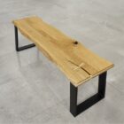 Träbänk med metallben på stengolv.