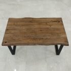 Rustikt träbord med metallben på stengolv.