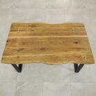 Rustikt träbord med metallben på klinkergolv.