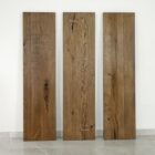 Tre stående träplankor mot väggen.