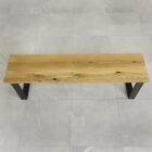 Träbänk med svarta metallben på kakelgolv.