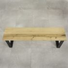 Träbänk med metallben på stengolv.