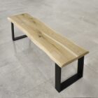 Träbänk med metallben på stengolv.