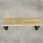 Träbänk med metallben på stengolv.