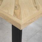 Träbordshörn med metallben över stengolv.