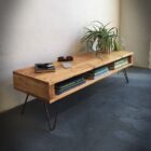 Träbänk med böcker och växt i rumshörna.