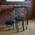 Tre svarta metallbord mot tegelvägg.