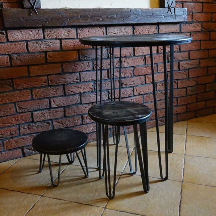 HAIRPINA_14.jpg Tre svarta metallbord mot tegelvägg.